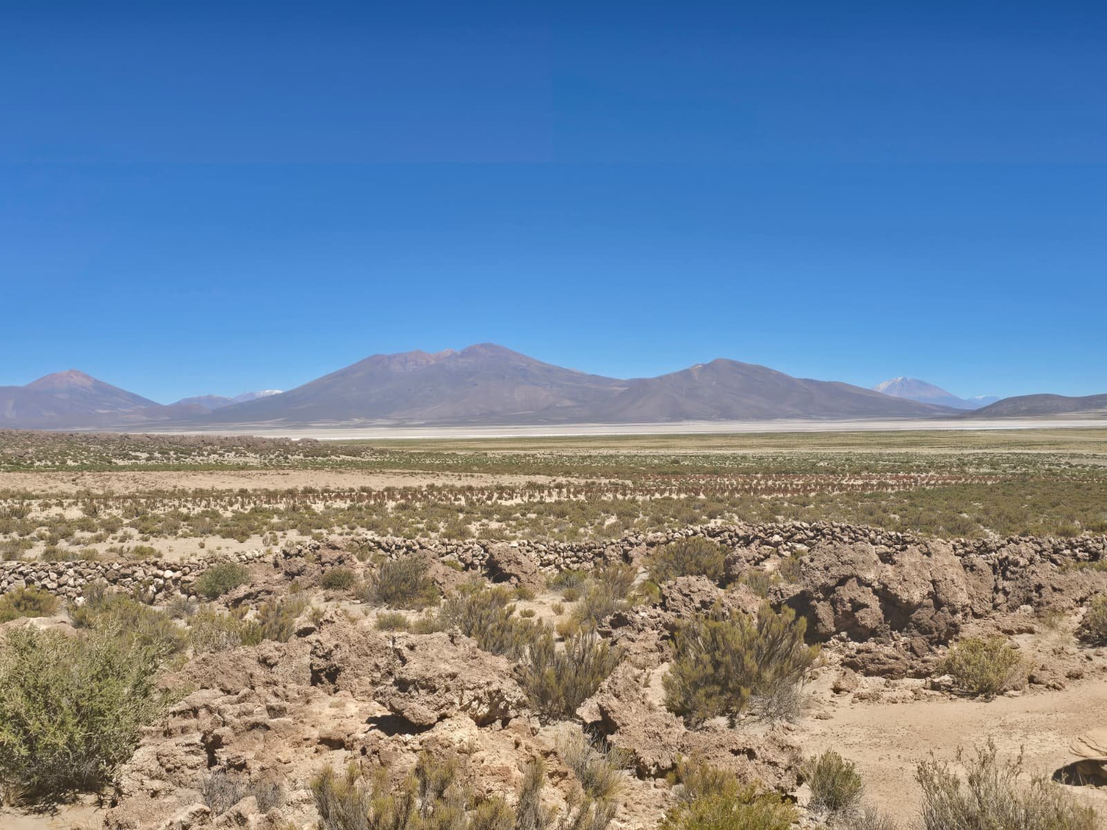 Panorama altiplano z Salar de Uyuni na horyzoncie między wulkanami